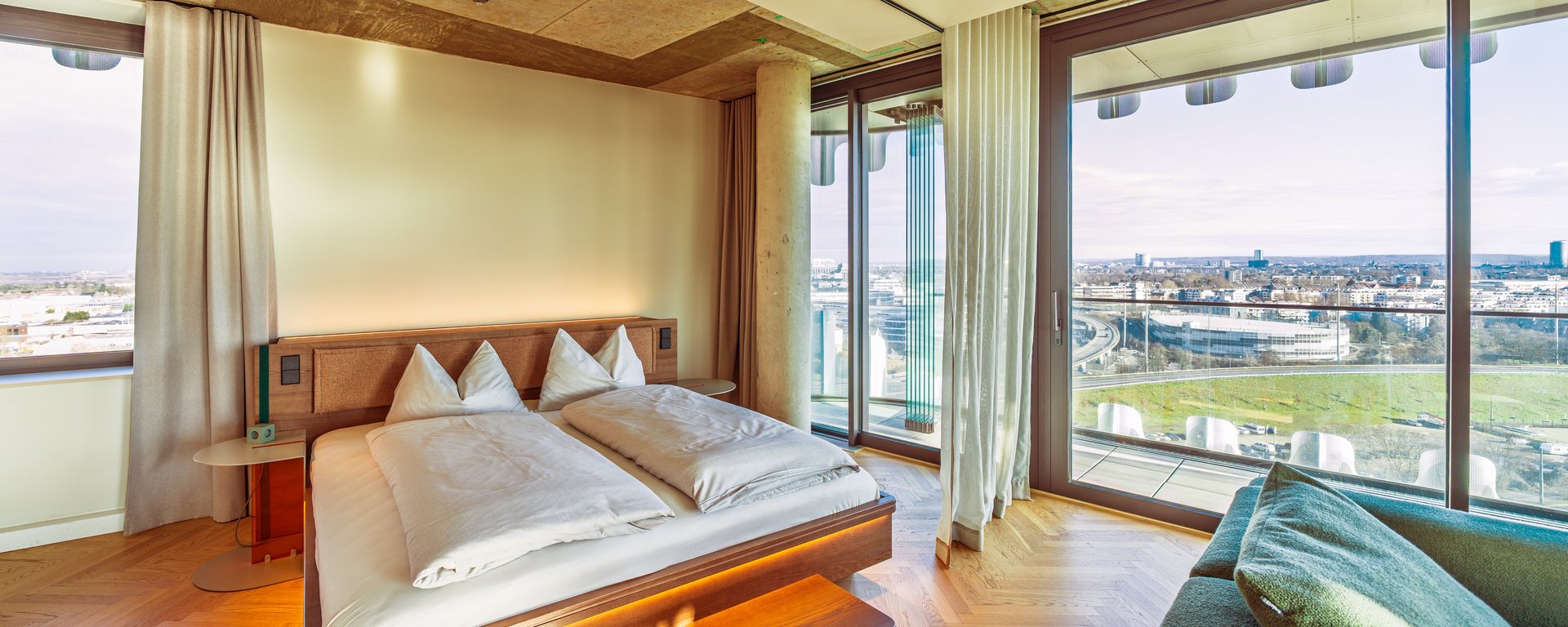 Schlafbereich im Apartment Home Skyline mit Doppelbett und direktem Ausblick über die Skyline.