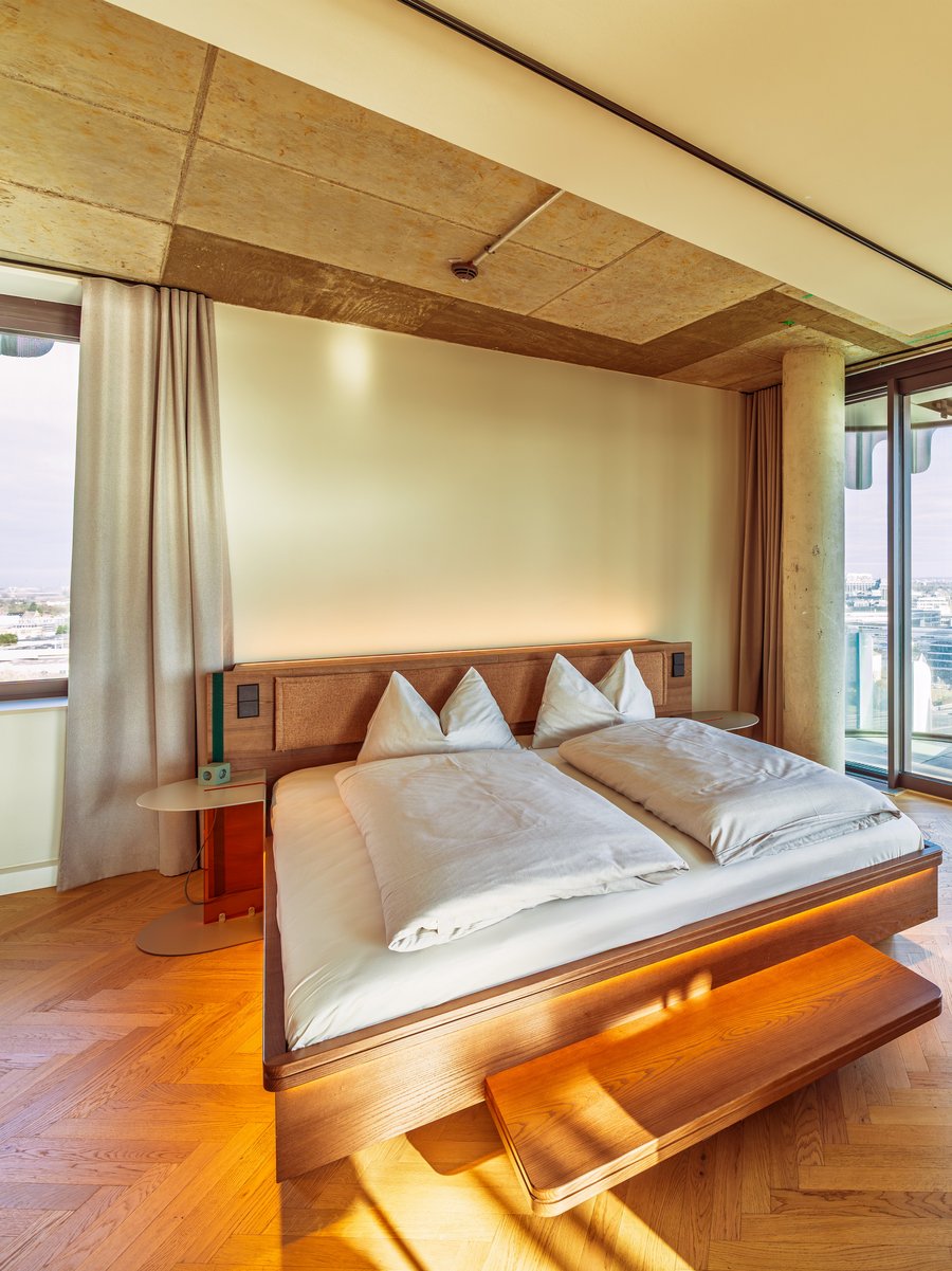 Schlafbereich im Apartment Home Skyline mit Doppelbett und direktem Ausblick über die Skyline.