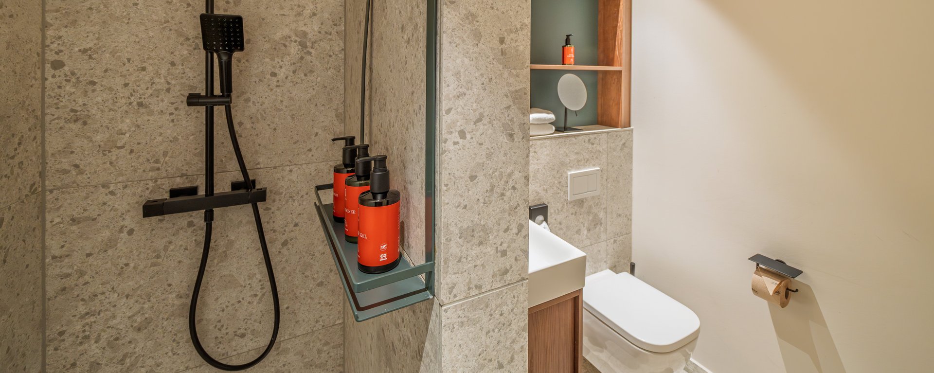 Detailansicht der Dusche mit Regenduschkopf und hochwertigen Pflegeprodukten im The Zipper Hotel.