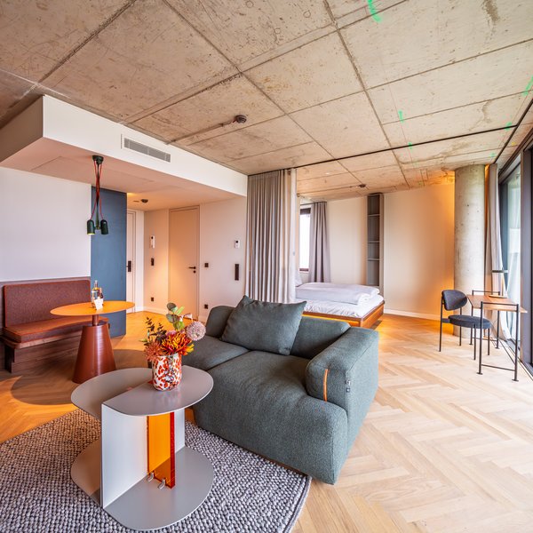 Gemütliche Sitzecke im Apartment Home mit grünem Sofa, Designtisch und großen Fensterfronten.