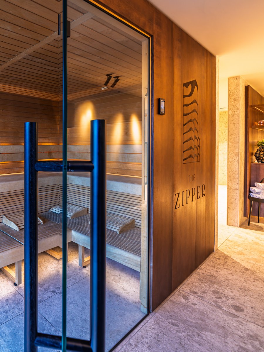 Moderne Holzsauna mit Glasfront und indirekter Beleuchtung im Wellnessbereich des Hotels.