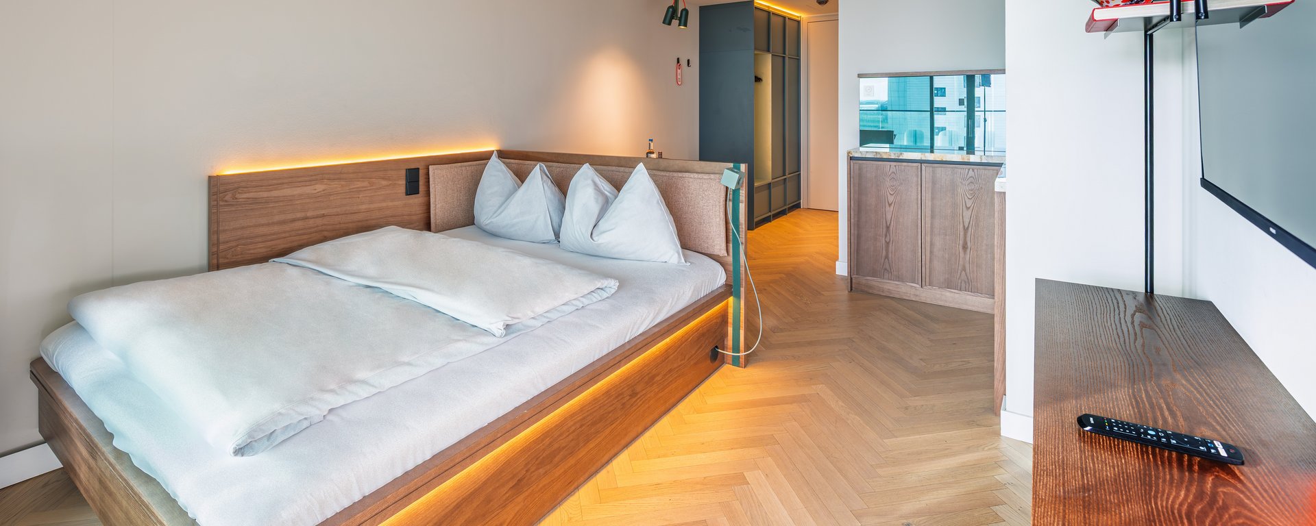 Blick auf das gemütliche Doppelbett und den Arbeitsbereich im The Zipper Hotel und Apartments.