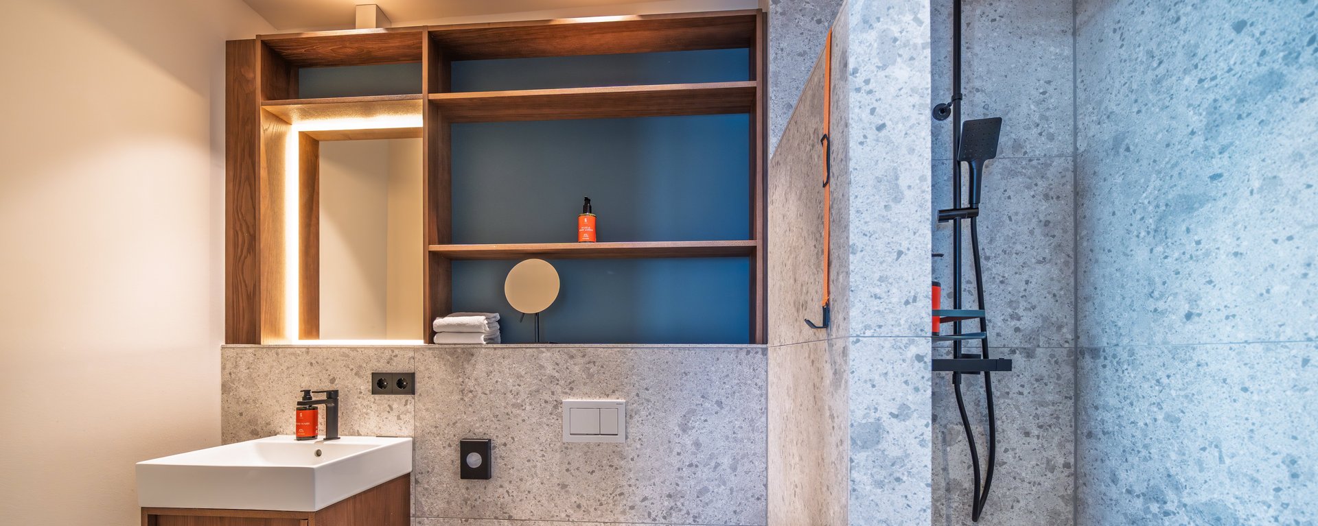 Modernes Badezimmer der Suite Loggia mit großzügigem Waschtisch, Spiegel und Naturstein-Design.