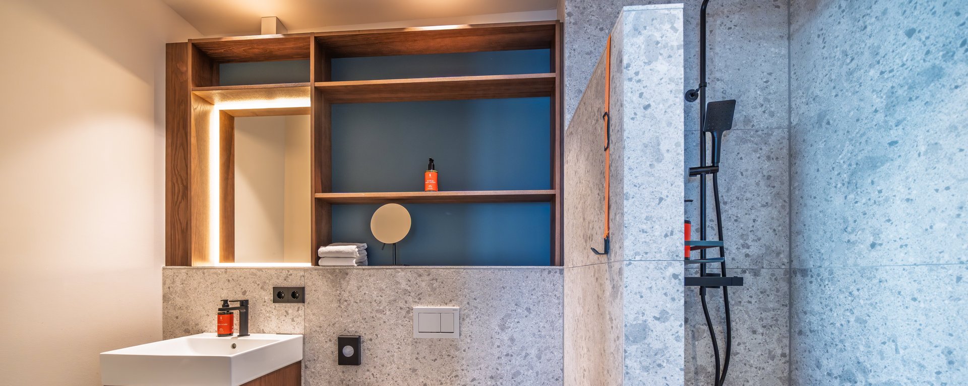 Modernes Badezimmer der Suite Loggia mit großzügigem Waschtisch, Spiegel und Naturstein-Design.