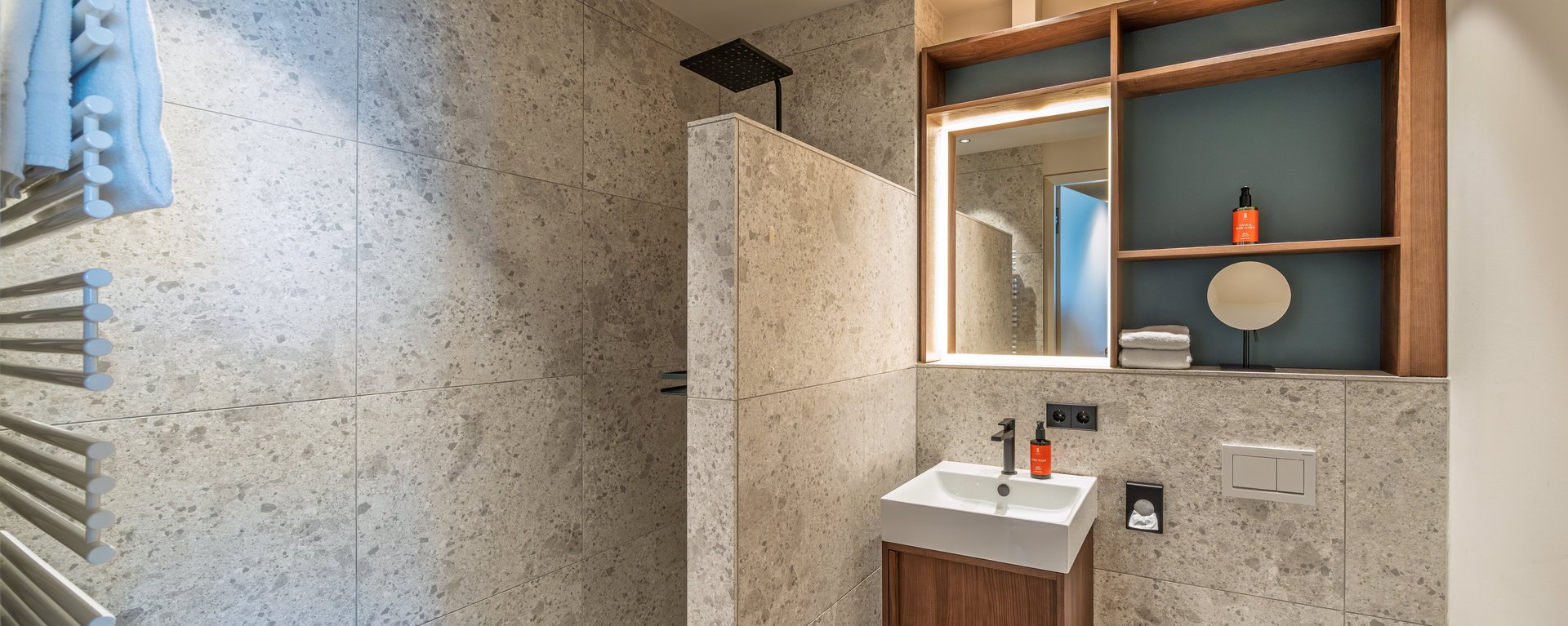 Helles Badezimmer mit ebenerdiger Dusche, WC und Handtuchwärmer in hochwertiger Optik.