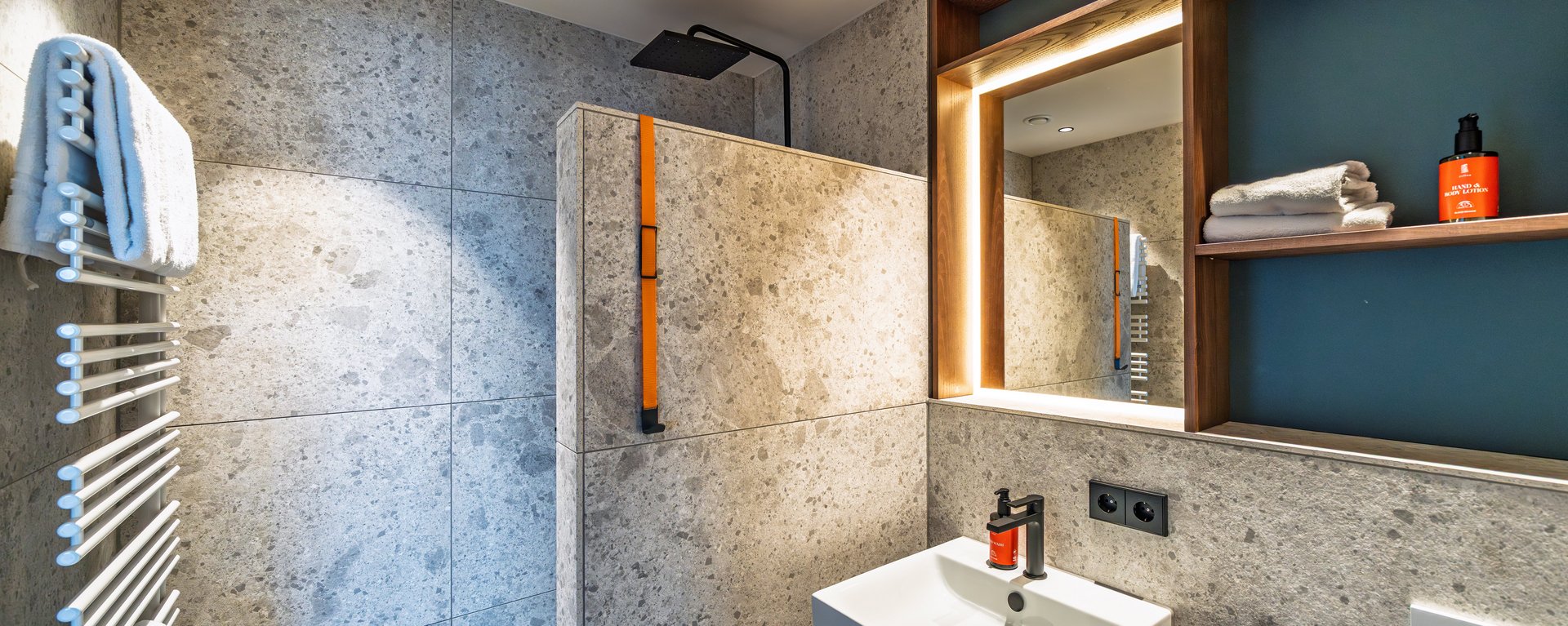 Modernes Badezimmer im Apartment Home mit Waschtisch aus Holz, großem Spiegel und Handtuchheizkörper.