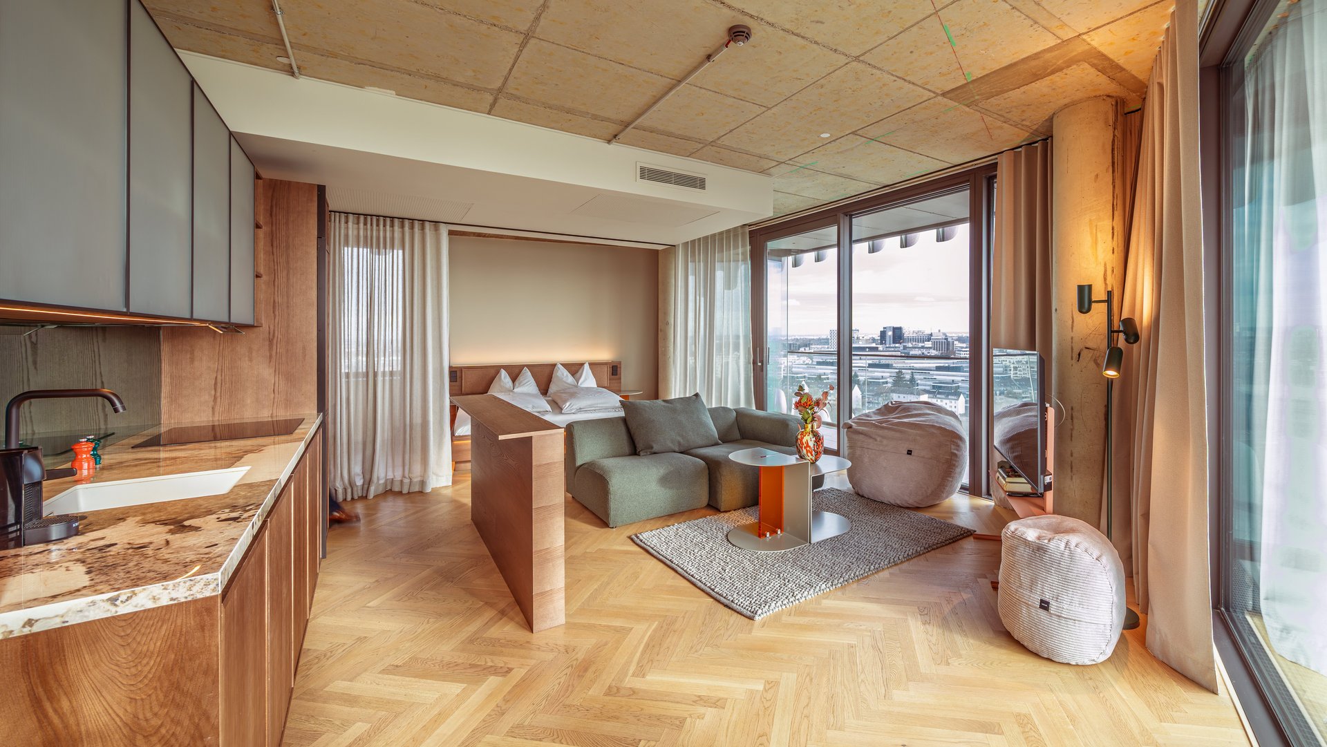 Panorama-Blick in das Apartment Home Skyline mit offener Wohnküche und bodentiefen Fenstern.