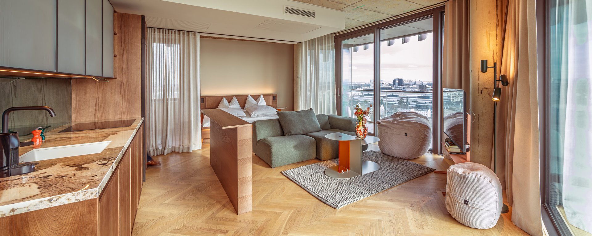 Panorama-Blick in das Apartment Home Skyline mit offener Wohnküche und bodentiefen Fenstern.