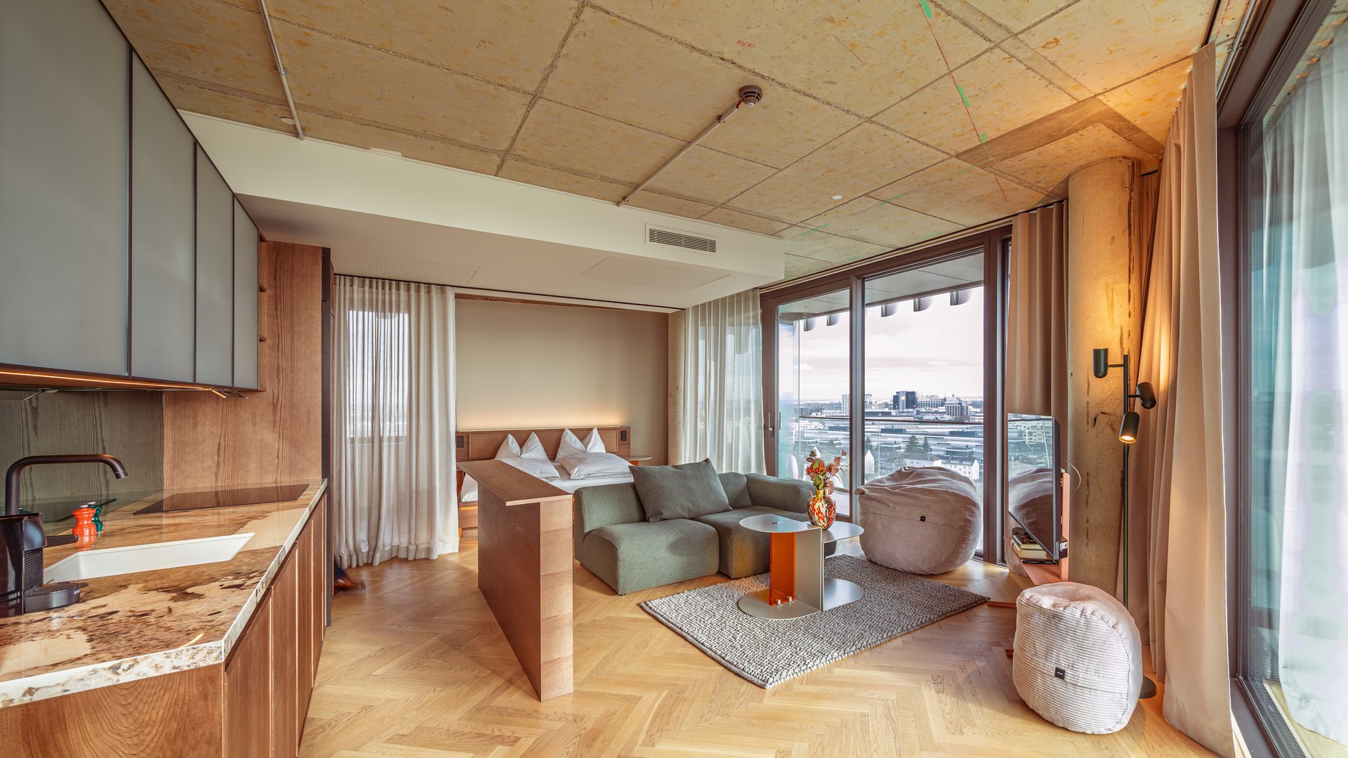 Panorama-Blick in das Apartment Home Skyline mit offener Wohnküche und bodentiefen Fenstern.