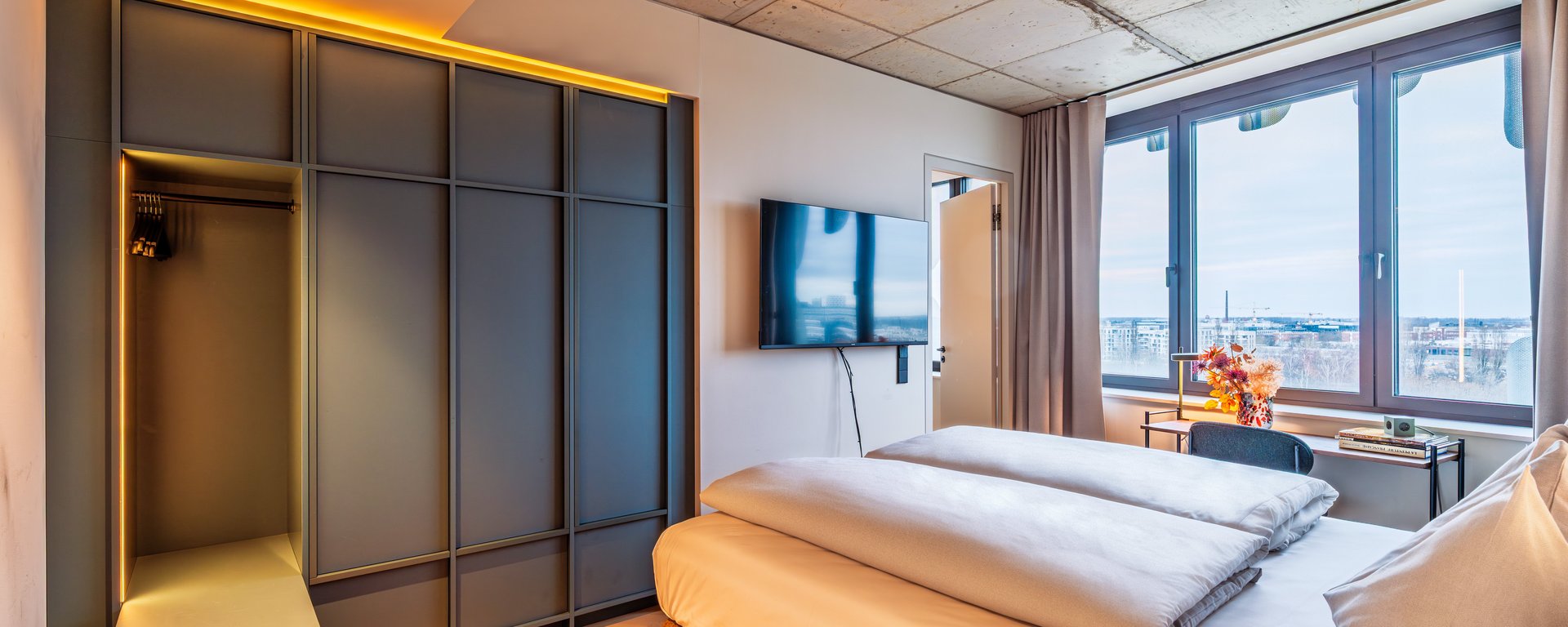 Separates Schlafzimmer der Apartment Suite mit großem Doppelbett, Einbauschränken und Panoramafenster.