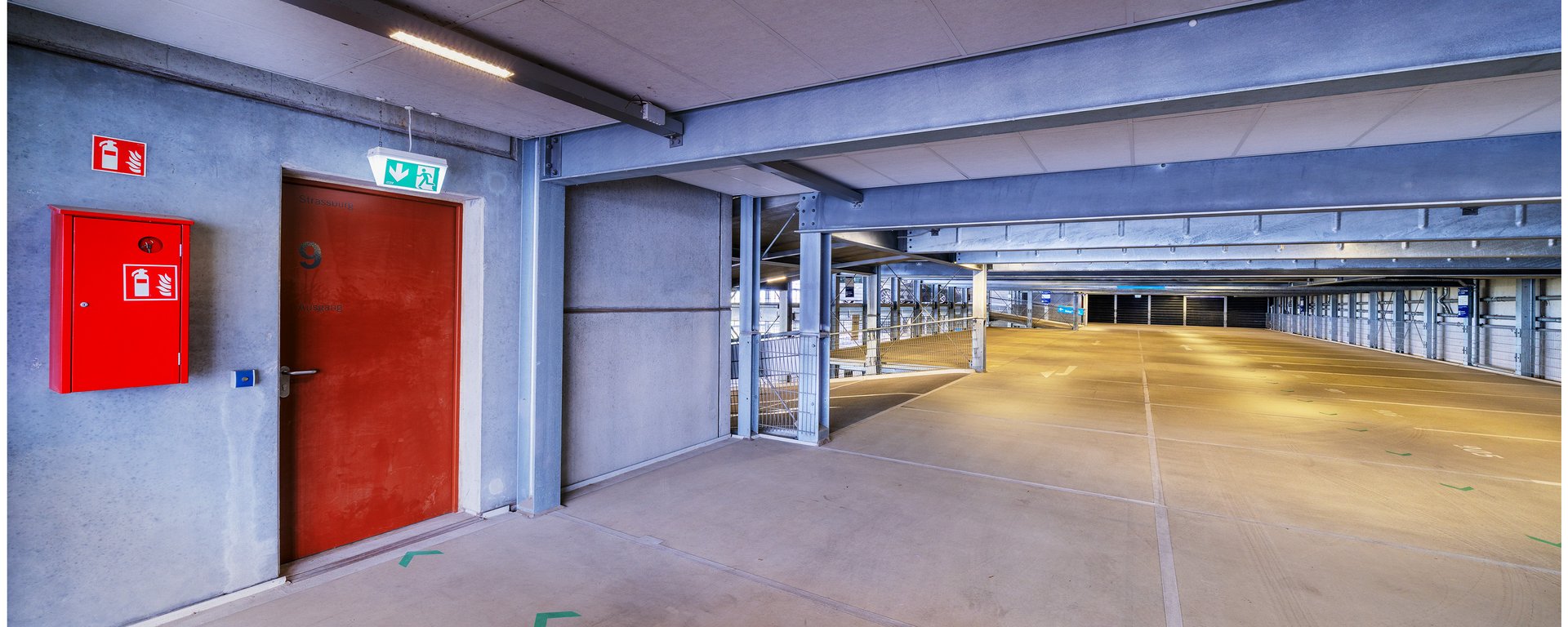 Eine Ecke auf einem Parkdeck mit einer auffälligen roten Brandschutztür.