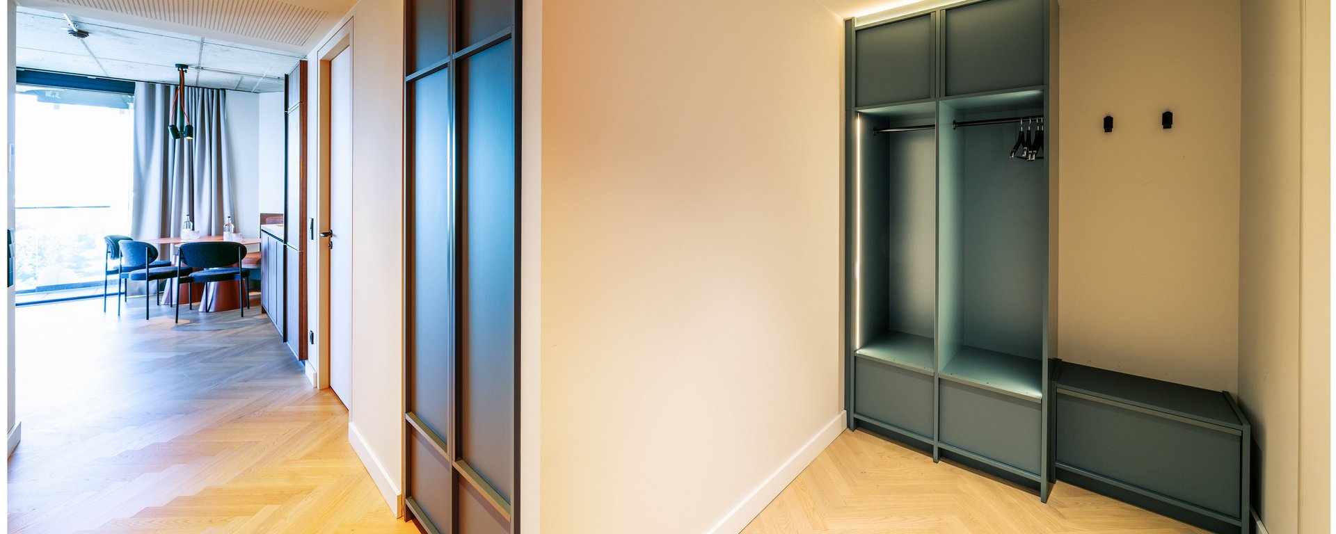 Eingangsbereich einer Suite im THE ZIPPER Hotel Düsseldorf mit Garderobe und Blick in den Wohnbereich.