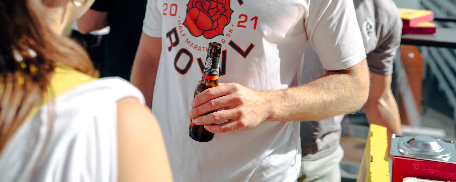 Junger Mann mit Sonnenbrille und Getränk in der Hand bei einem Outdoor-Event in Düsseldorf.