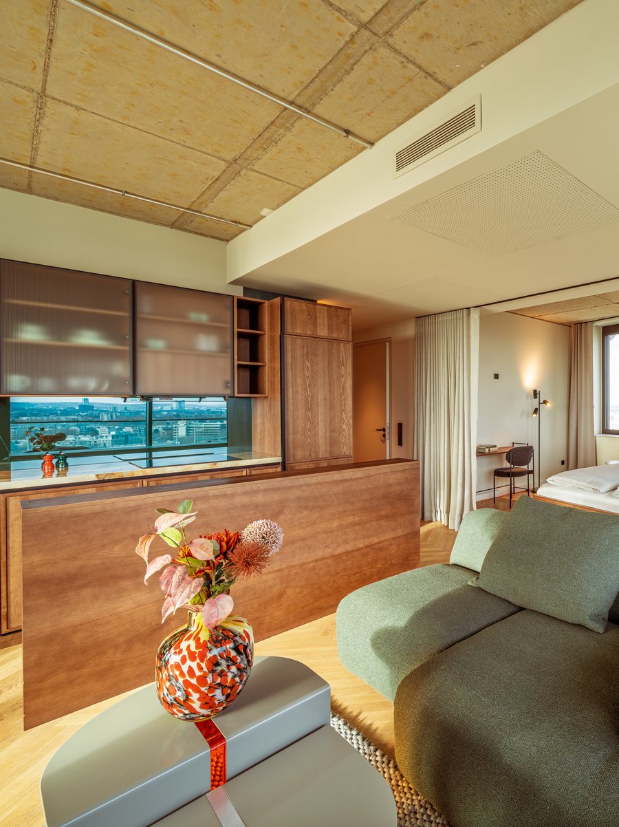 Gemütliches Wohnzimmer im Apartment Home Skyline mit grünem Sofa und Blick Richtung Schlafbereich.