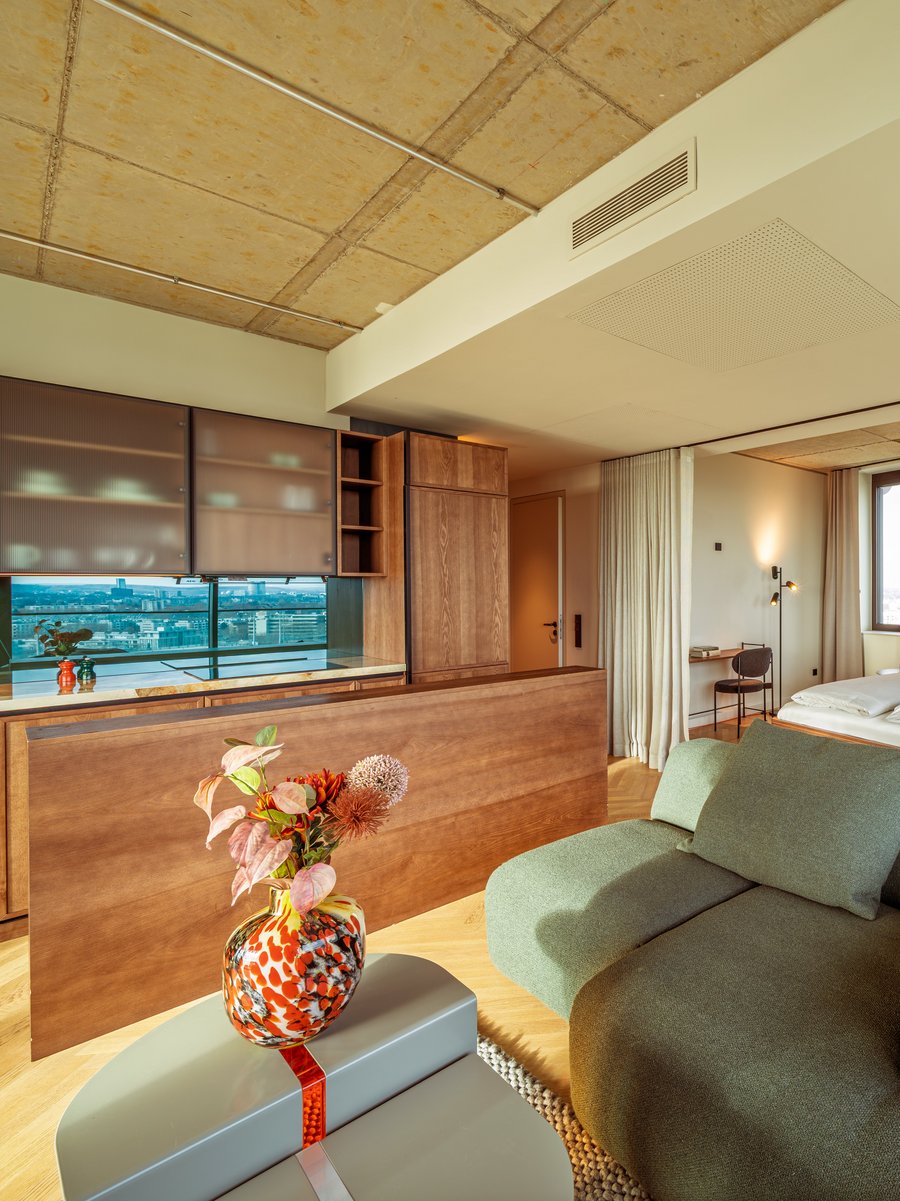 Gemütliches Wohnzimmer im Apartment Home Skyline mit grünem Sofa und Blick Richtung Schlafbereich.