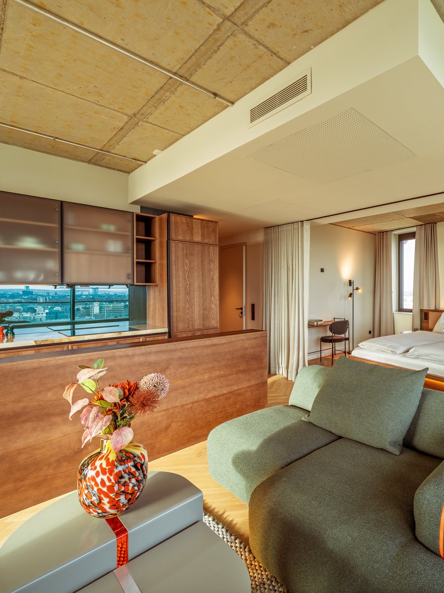 Gemütliches Wohnzimmer im Apartment Home Skyline mit grünem Sofa und Blick Richtung Schlafbereich.