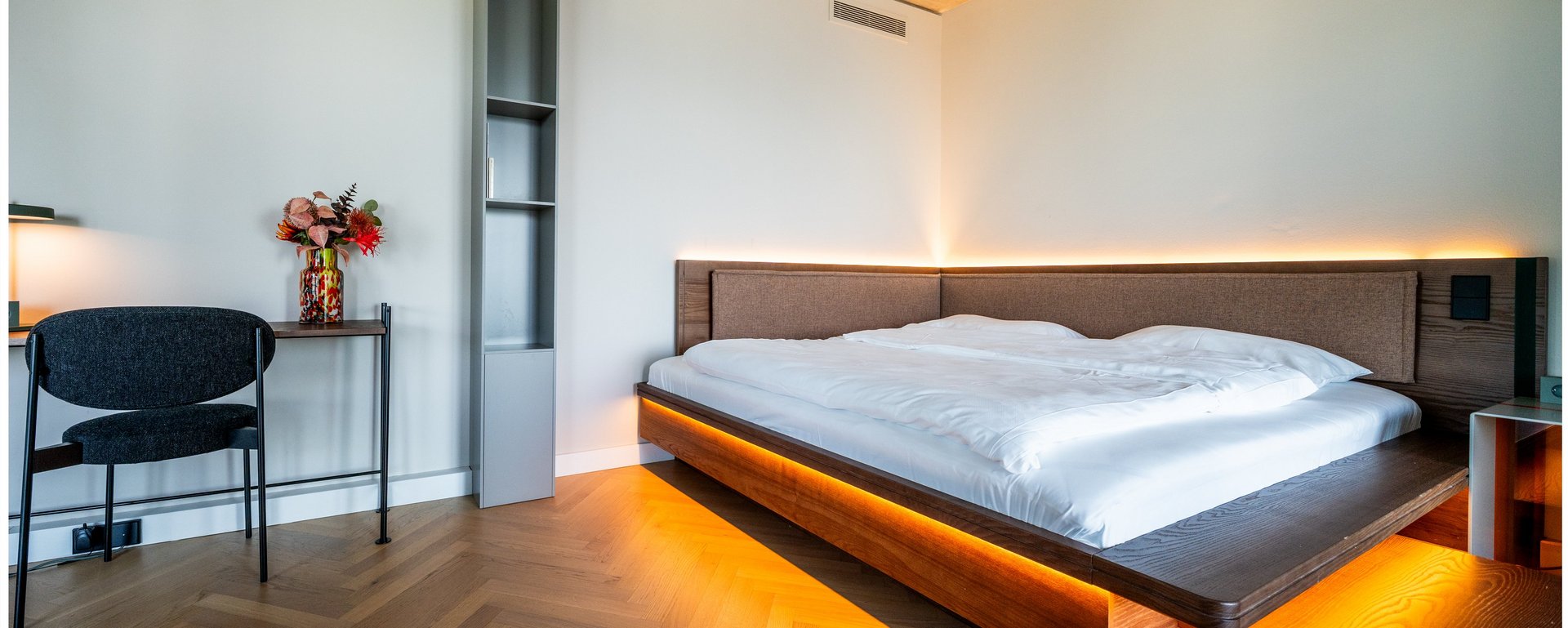 Modernes Hotelzimmer mit großem Doppelbett, Schreibtisch und stilvoller Beleuchtung im THE ZIPPER Hotel Düsseldorf.