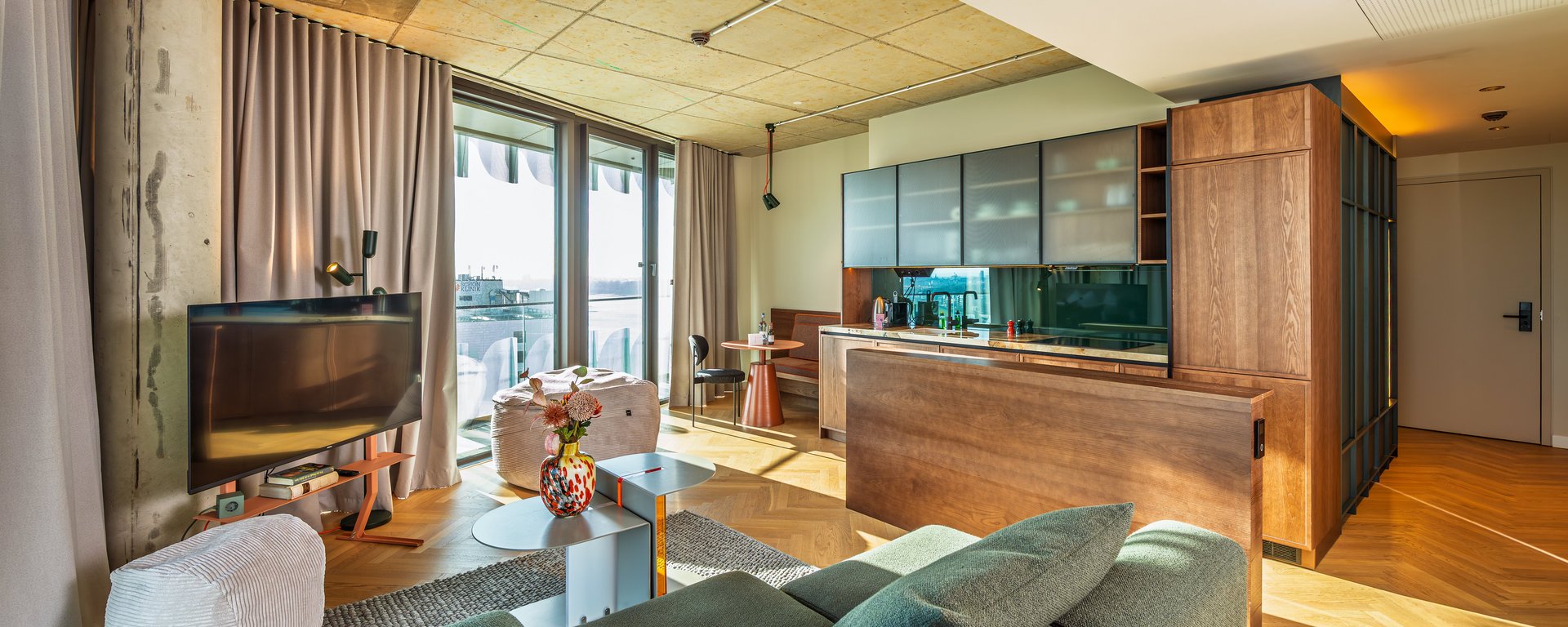 Helles Wohnzimmer im The Zipper mit modernem Mobiliar, Parkettboden und Zugang zur Loggia.