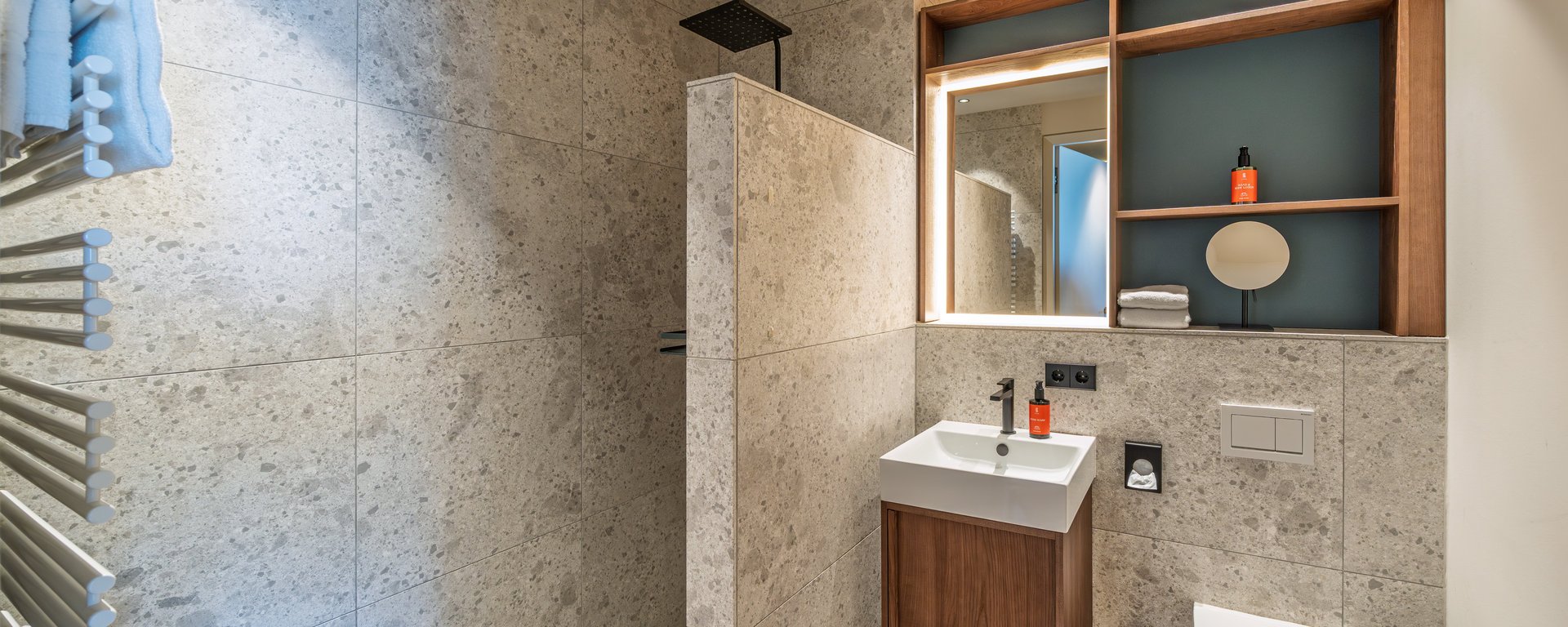 Helles Badezimmer der Suite mit WC, Waschtisch und Handtuchwärmer in Stein-Optik.