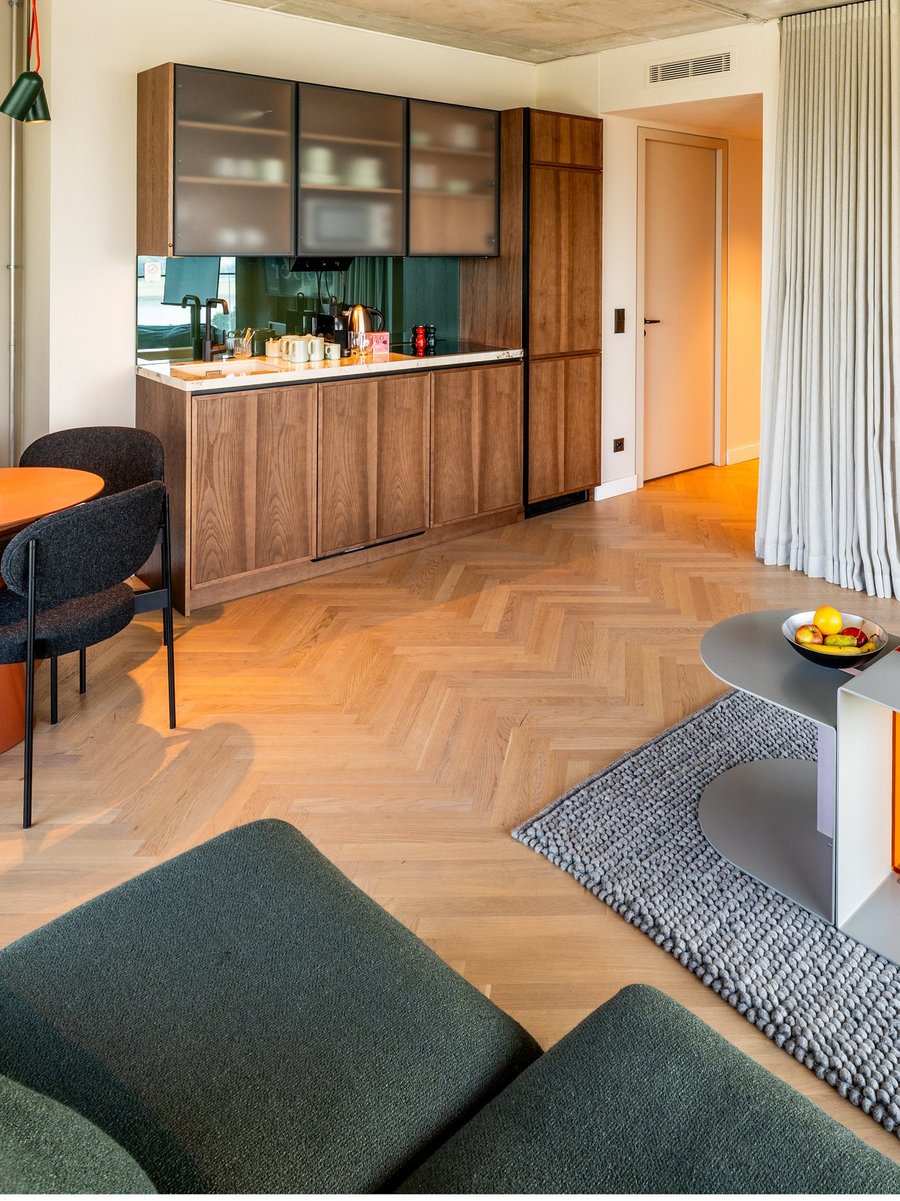 Moderne Hotelsuite mit Küchenzeile, Esstisch, Sofa und TV im THE ZIPPER Hotel Düsseldorf.