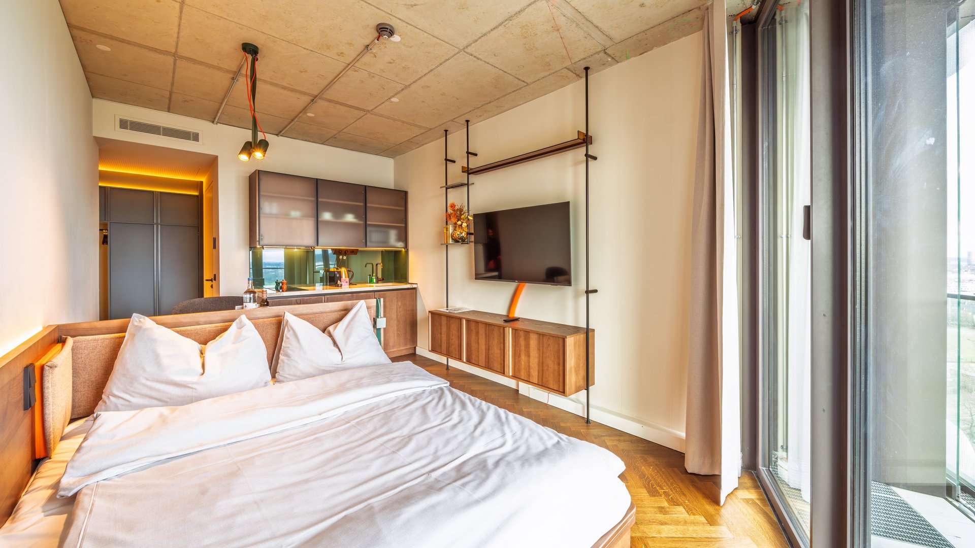 Schlafbereich im Apartment Skyline mit gemütlichem Doppelbett, Parkettboden und Blick auf den Flat-TV.