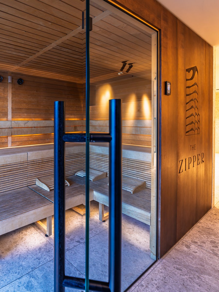 Moderne Holzsauna mit Glasfront und indirekter Beleuchtung im Wellnessbereich des Hotels.