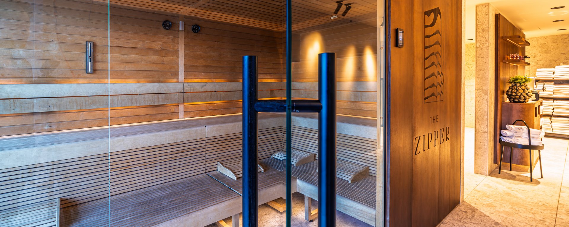 Moderne Holzsauna mit Glasfront und indirekter Beleuchtung im Wellnessbereich des Hotels.