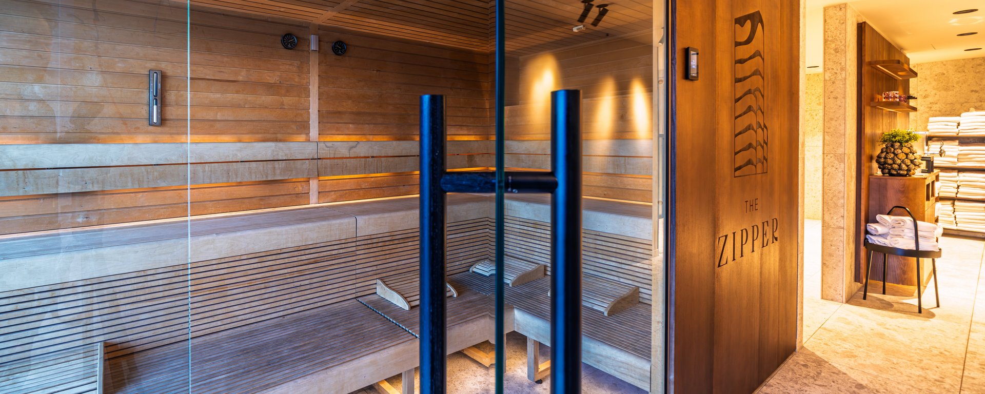 Moderne Holzsauna mit Glasfront und indirekter Beleuchtung im Wellnessbereich des Hotels.