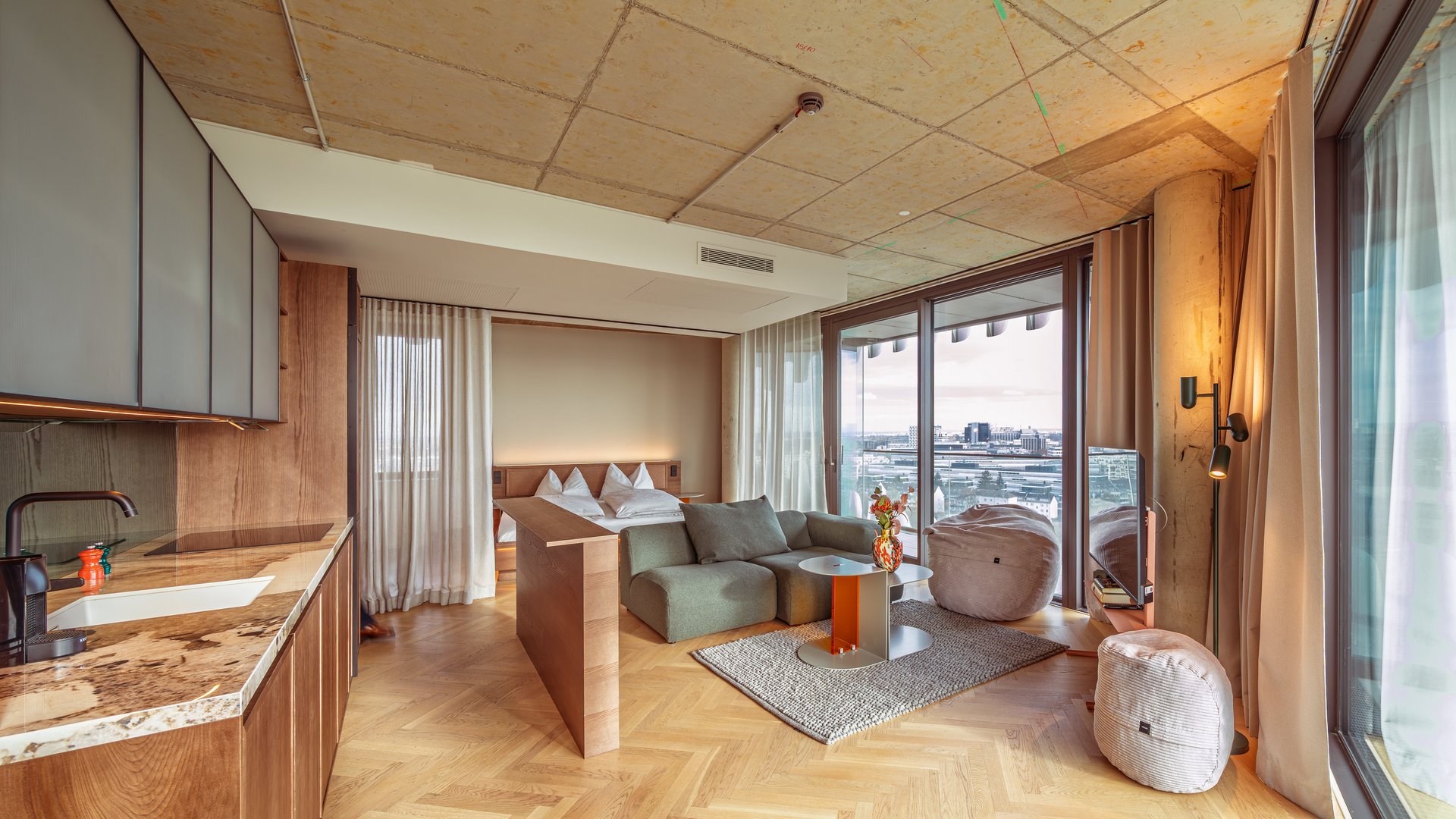 Panorama-Blick in das Apartment Home Skyline mit offener Wohnküche und bodentiefen Fenstern.