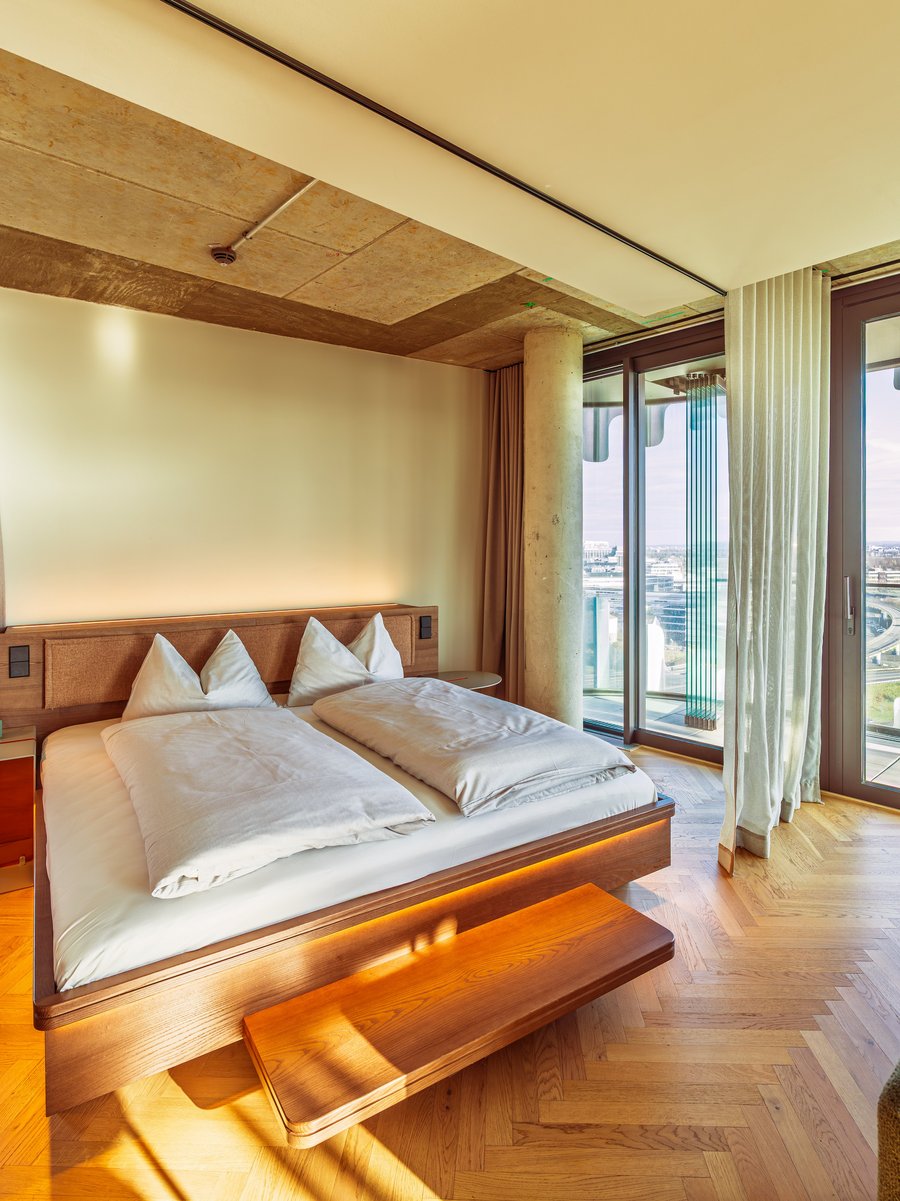 Schlafbereich im Apartment Home Skyline mit Doppelbett und direktem Ausblick über die Skyline.