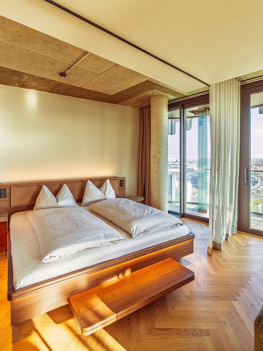 Schlafbereich im Apartment Home Skyline mit Doppelbett und direktem Ausblick über die Skyline.