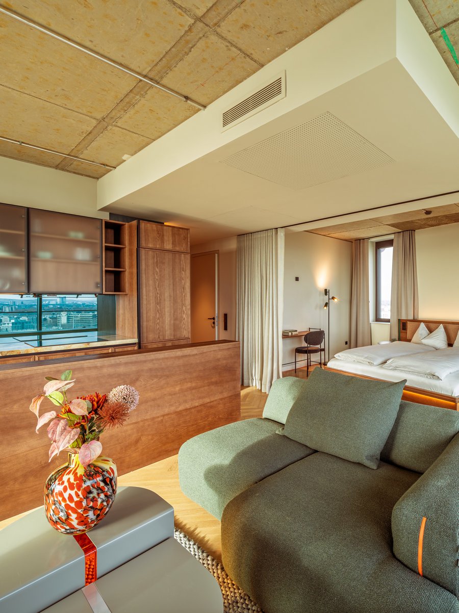 Gemütliches Wohnzimmer im Apartment Home Skyline mit grünem Sofa und Blick Richtung Schlafbereich.