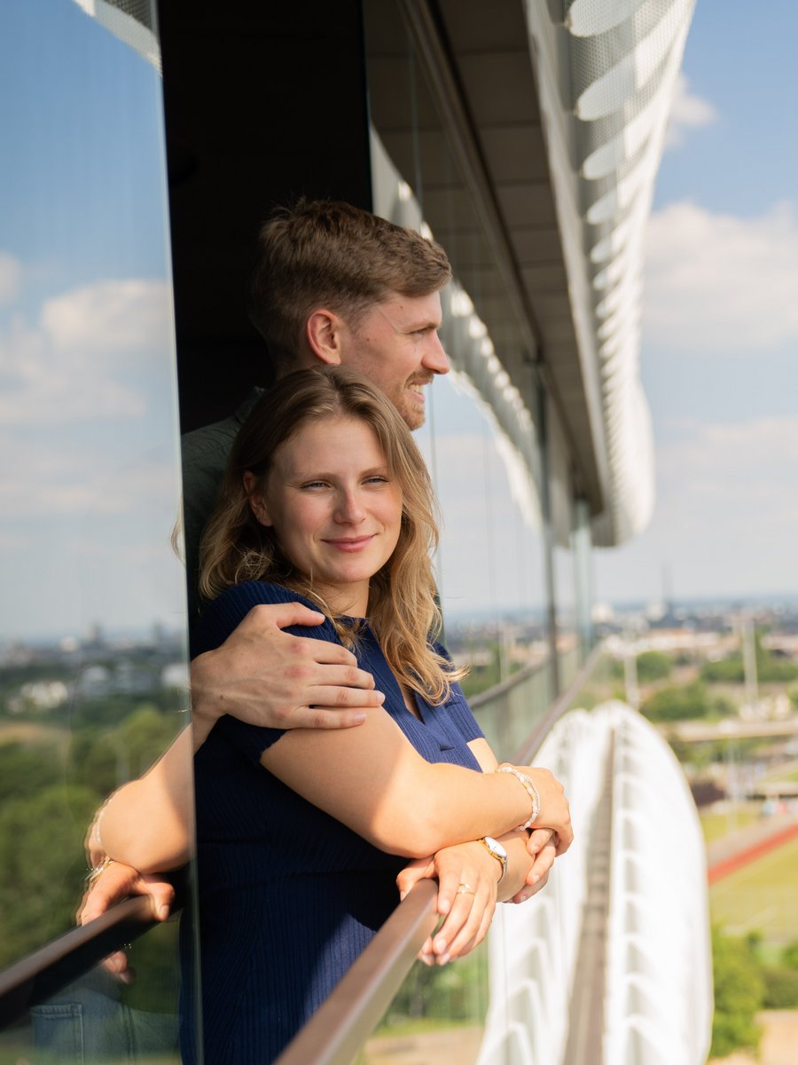 Paar auf dem Balkon eines Apartments im The Zipper Düsseldorf mit weitem Blick über die Stadt und ins Grüne – ideal für Wohnen auf Zeit oder als Ersatzwohnung.