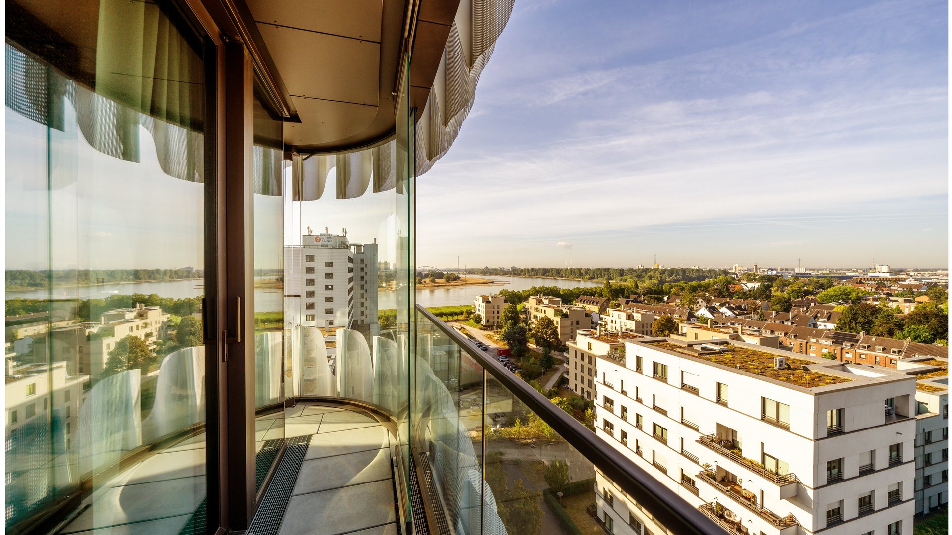 Balkon einer Suite mit Glasgeländer und weitem Blick über Düsseldorf im THE ZIPPER Hotel.