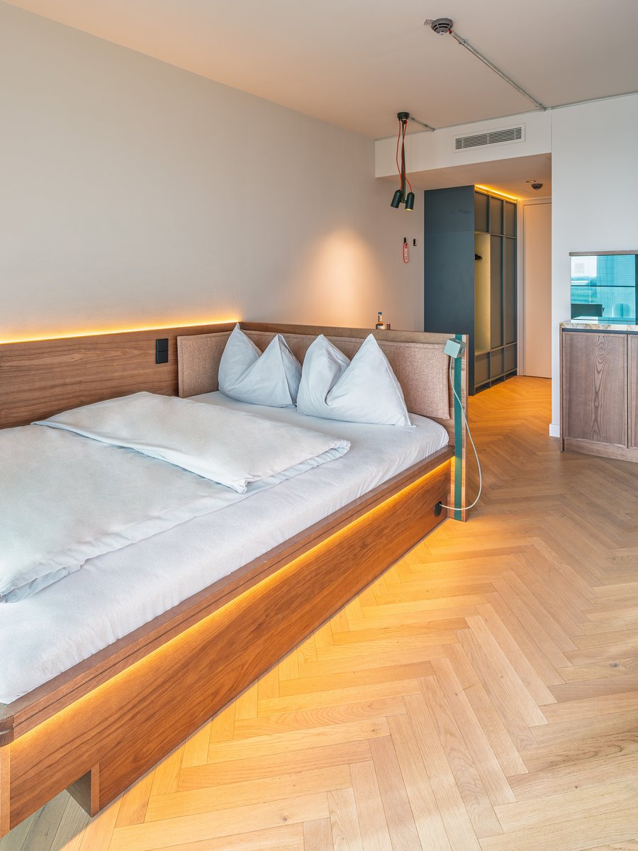 Blick auf das gemütliche Doppelbett und den Arbeitsbereich im The Zipper Hotel und Apartments.