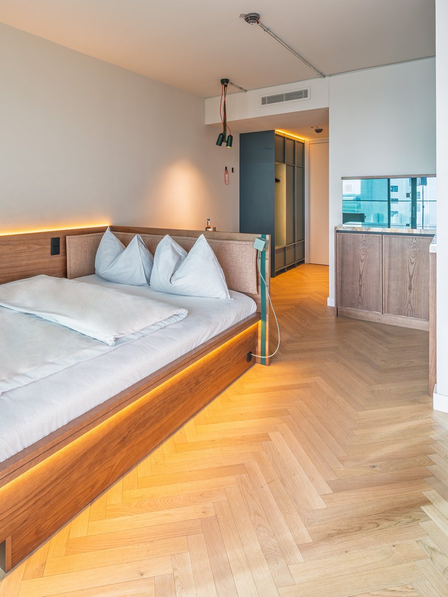 Blick auf das gemütliche Doppelbett und den Arbeitsbereich im The Zipper Hotel und Apartments.