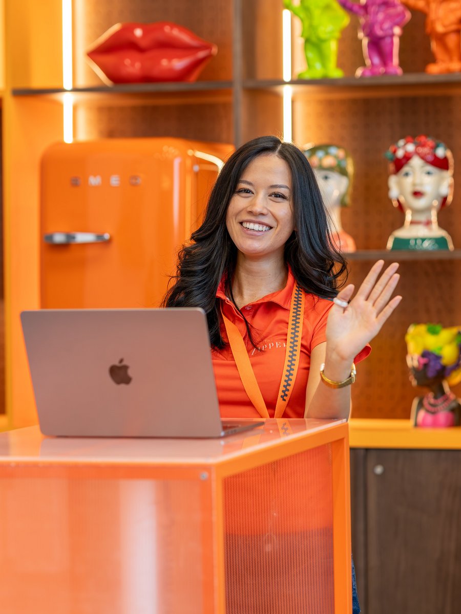 Eine lächelnde Mitarbeiterin in orangefarbenem Poloshirt