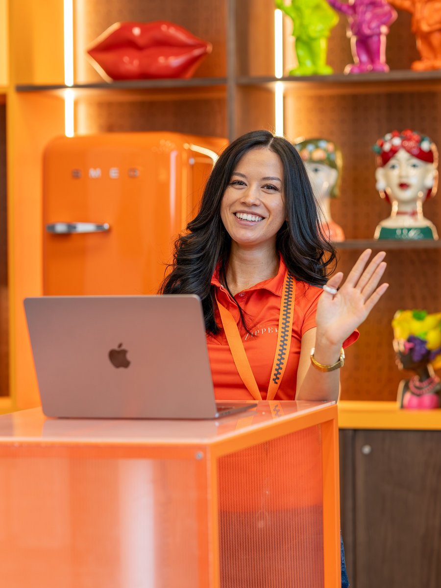 Eine lächelnde Mitarbeiterin in orangefarbenem Poloshirt