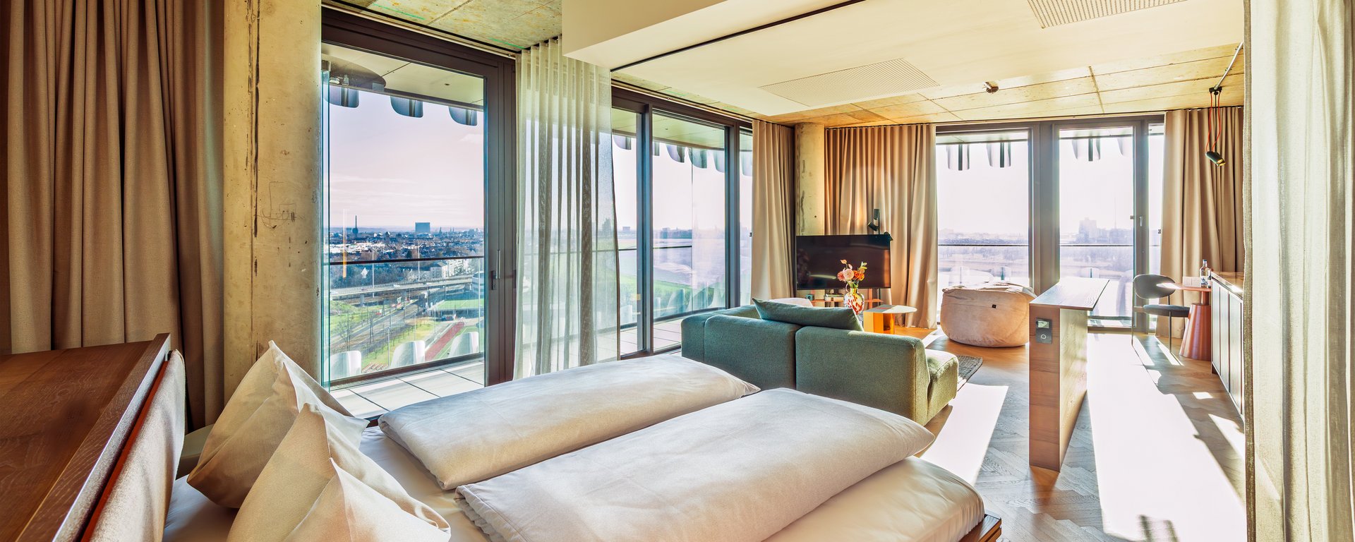 Perspektive vom Bett aus in den lichtdurchfluteten Wohnbereich des Skyline Apartments.