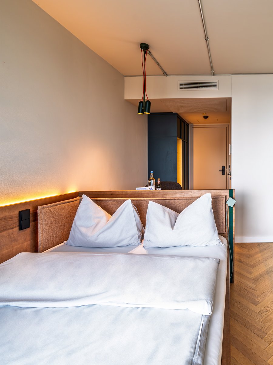 Perspektive vom Bett aus in das Apartment des The Zipper Hotels, inklusive TV-Wand und Einbauschränken aus Holz.